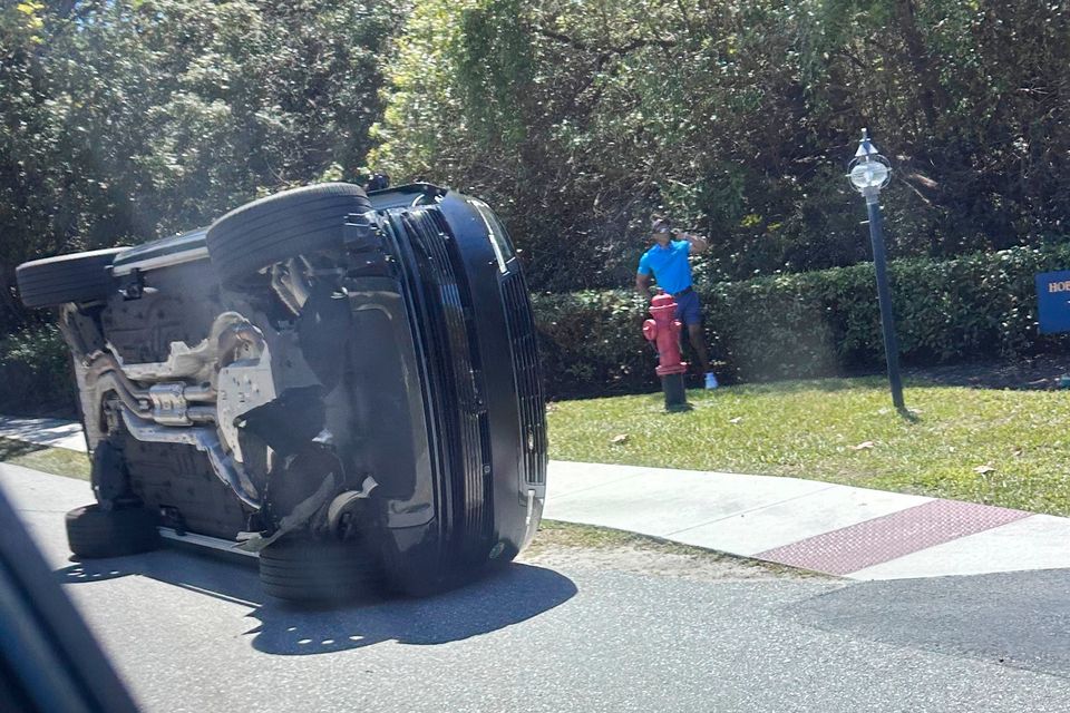 Golfer Tiger Woods stands by his overturned vehicle in Jupiter Island